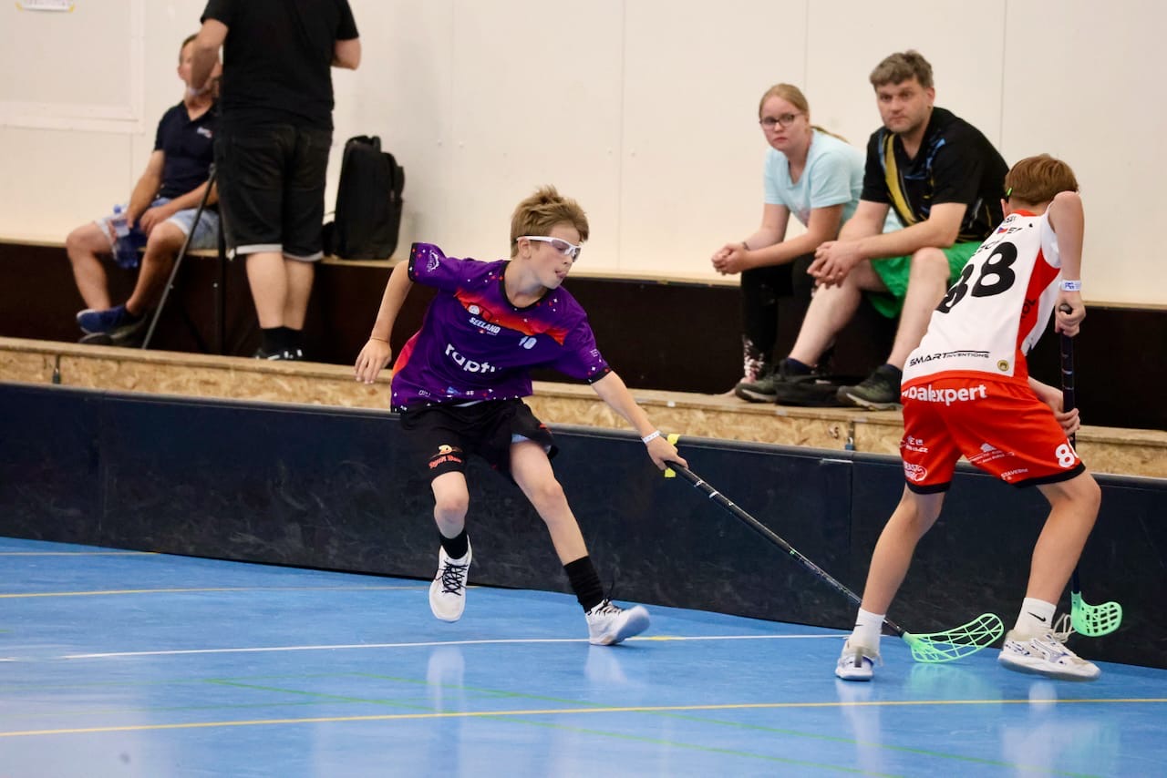 Tim im violetten Trikot führt den Ball an der Bande